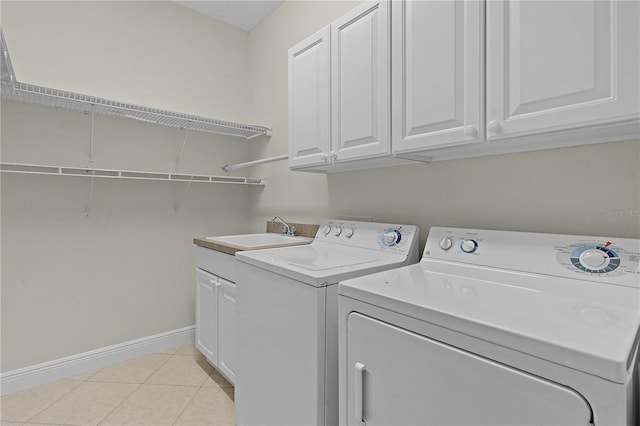 washroom featuring separate washer and dryer, sink, light tile patterned floors, and cabinets