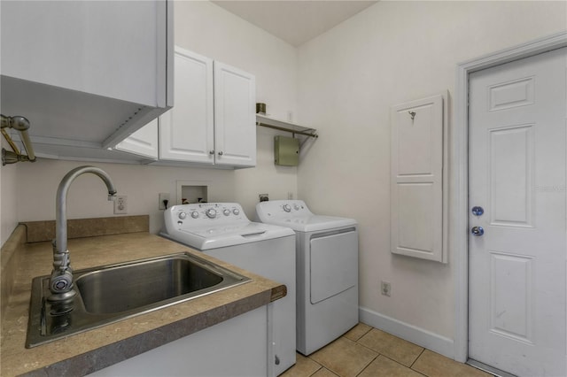 clothes washing area featuring cabinets, sink, washer and dryer, and light tile patterned floors