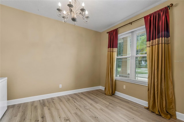 unfurnished room featuring a chandelier and light hardwood / wood-style floors