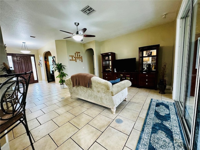 living room with light tile patterned floors, a textured ceiling, and ceiling fan