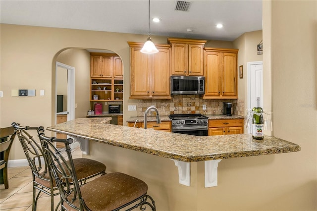 kitchen with stainless steel appliances, light stone countertops, light tile patterned floors, and backsplash