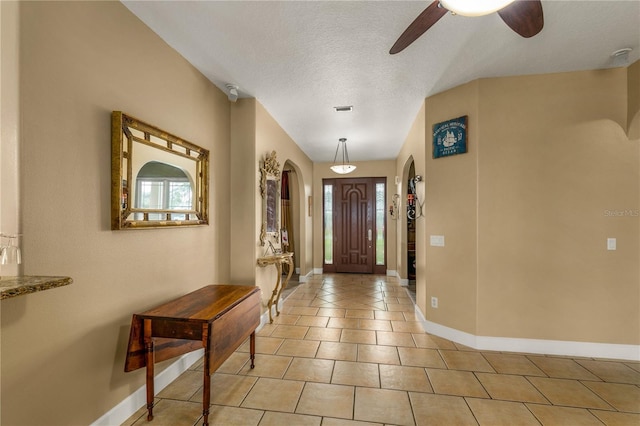 foyer featuring ceiling fan, a wealth of natural light, light tile patterned floors, and a textured ceiling