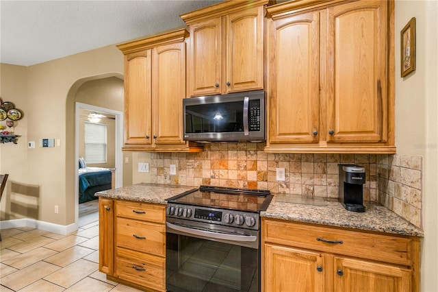 kitchen with tasteful backsplash, light tile patterned flooring, light stone countertops, and appliances with stainless steel finishes