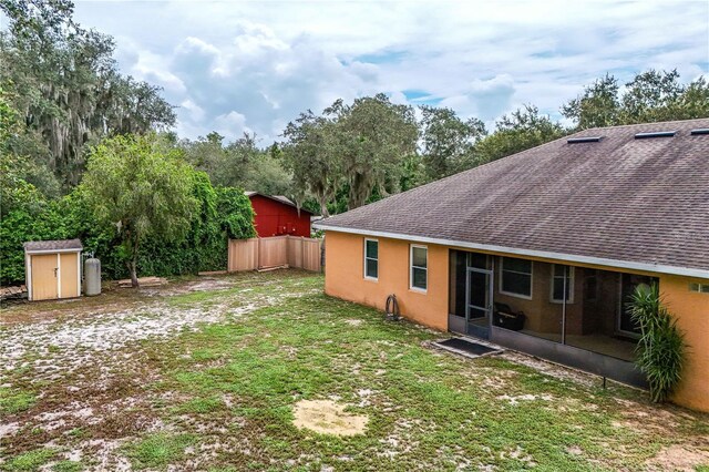 view of yard featuring a sunroom and a storage unit