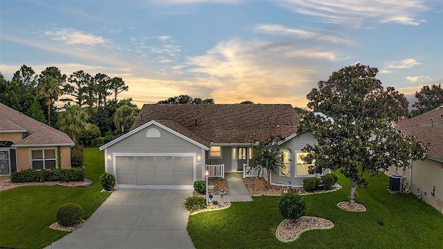 ranch-style home featuring driveway, an attached garage, central AC unit, and a yard