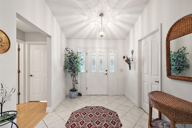 foyer with light tile patterned floors, baseboards, and a textured ceiling