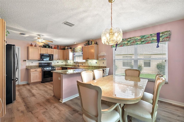 kitchen with stainless steel appliances, visible vents, hanging light fixtures, and a kitchen island