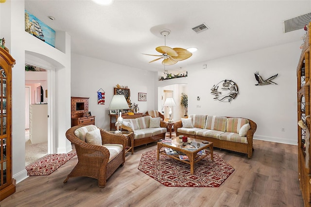 living room with a ceiling fan, arched walkways, visible vents, and wood finished floors