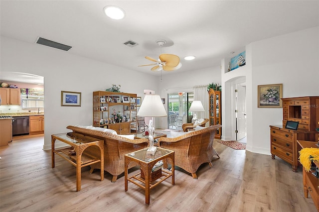 living area with arched walkways, ceiling fan, visible vents, baseboards, and light wood-type flooring