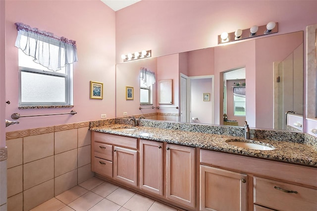 bathroom featuring tile patterned floors, a sink, tile walls, and double vanity