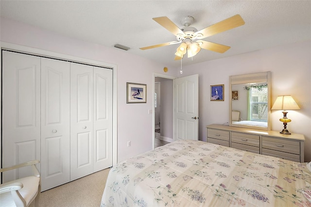 bedroom with light carpet, a ceiling fan, visible vents, and a closet