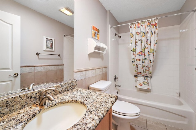 full bathroom featuring a textured ceiling, toilet, tile walls, vanity, and shower / bathtub combination with curtain