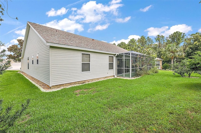 rear view of house with roof with shingles and a lawn