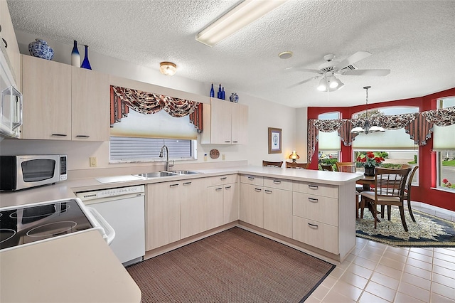 kitchen featuring sink, hanging light fixtures, white dishwasher, light tile patterned floors, and kitchen peninsula