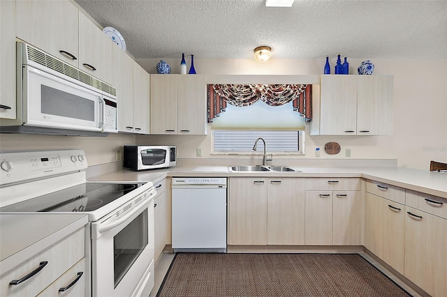 kitchen featuring dark colored carpet, light brown cabinetry, sink, a textured ceiling, and white appliances