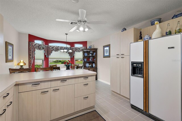 kitchen featuring light tile patterned flooring, a textured ceiling, light brown cabinets, and white refrigerator with ice dispenser