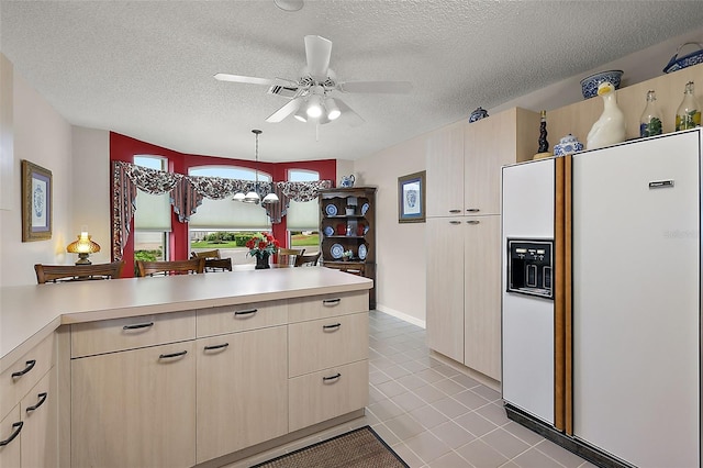 kitchen featuring hanging light fixtures, white fridge with ice dispenser, light countertops, and a textured ceiling