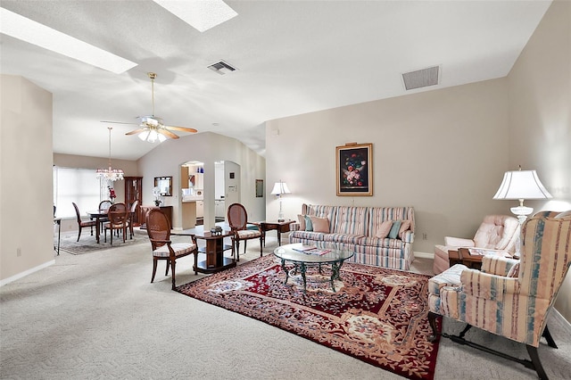 living room with light colored carpet, ceiling fan with notable chandelier, and vaulted ceiling with skylight