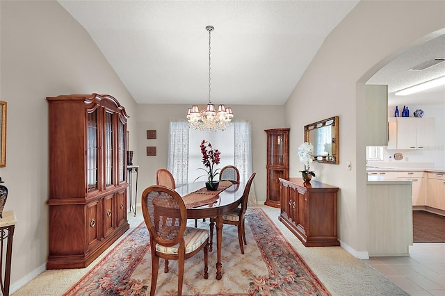 dining space with a notable chandelier, light tile patterned floors, and vaulted ceiling