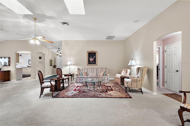 carpeted living room with ceiling fan and lofted ceiling with skylight