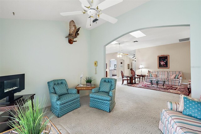 carpeted living room with ceiling fan and vaulted ceiling