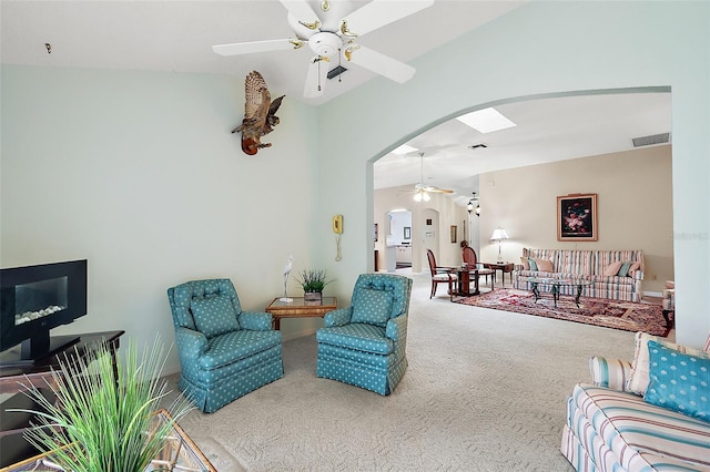 living room with carpet floors, arched walkways, visible vents, a ceiling fan, and vaulted ceiling