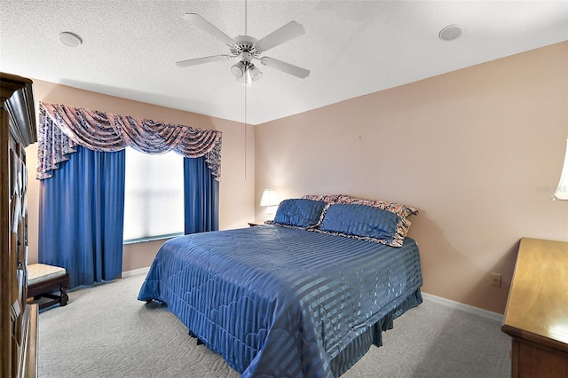 bedroom with light carpet, a textured ceiling, a ceiling fan, and baseboards