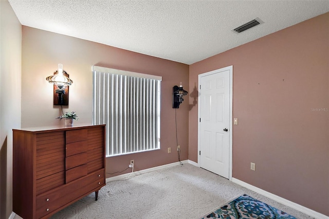 bedroom featuring a textured ceiling and light carpet