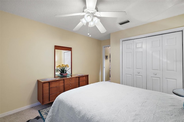 bedroom featuring ceiling fan, a closet, a textured ceiling, and light colored carpet