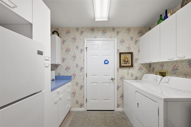 clothes washing area with wallpapered walls, cabinet space, baseboards, independent washer and dryer, and a textured ceiling