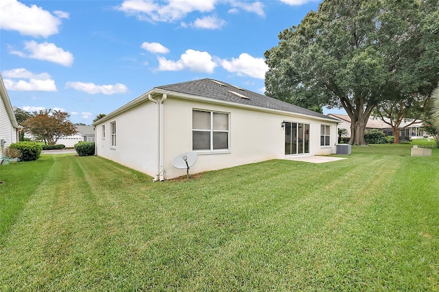 back of property featuring a lawn, cooling unit, and stucco siding