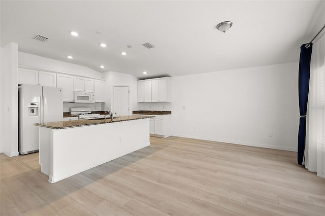 kitchen with white appliances, white cabinets, an island with sink, and light hardwood / wood-style flooring