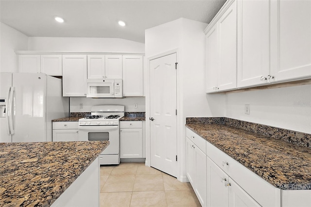 kitchen with white appliances, white cabinets, light tile patterned floors, and dark stone counters