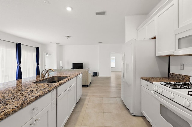 kitchen with dark stone counters, sink, white cabinetry, white appliances, and light tile patterned floors