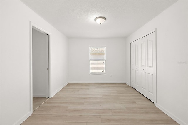 spare room with light hardwood / wood-style flooring and a textured ceiling