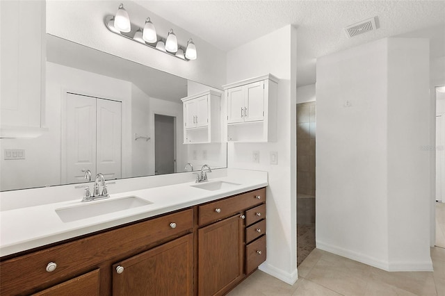 bathroom with tile patterned flooring, a textured ceiling, and vanity