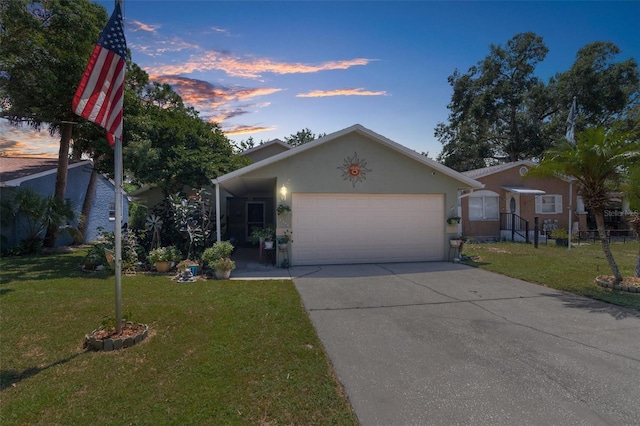 view of front of house with concrete driveway, a yard, an attached garage, and stucco siding