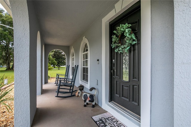 doorway to property featuring a porch and stucco siding