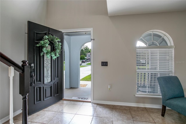 tiled foyer featuring baseboards and stairway