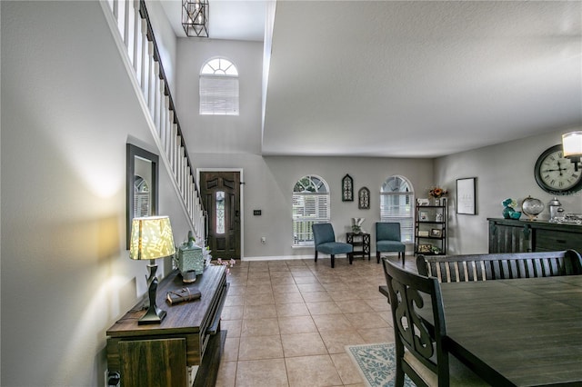 foyer entrance featuring light tile patterned floors, baseboards, and stairway