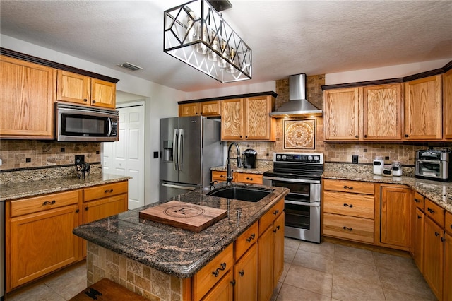 kitchen with stainless steel appliances, tasteful backsplash, visible vents, a sink, and wall chimney exhaust hood