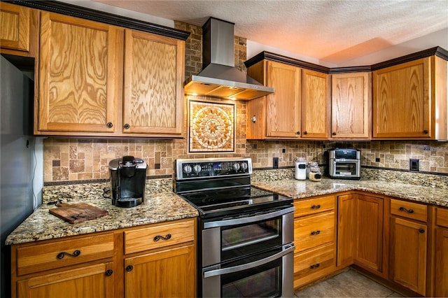 kitchen featuring fridge, wall chimney exhaust hood, double oven range, and tasteful backsplash