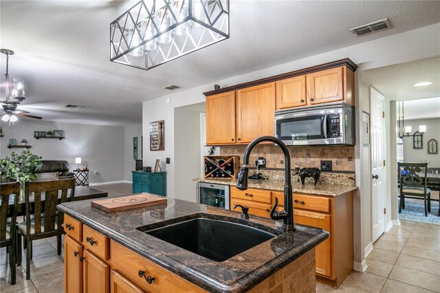 kitchen with light tile patterned floors, visible vents, stainless steel microwave, a sink, and backsplash