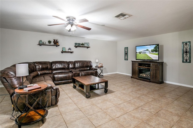 living room featuring a ceiling fan, a glass covered fireplace, visible vents, and baseboards