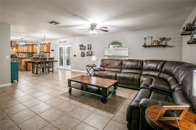 living room featuring french doors, visible vents, a textured ceiling, and light tile patterned floors