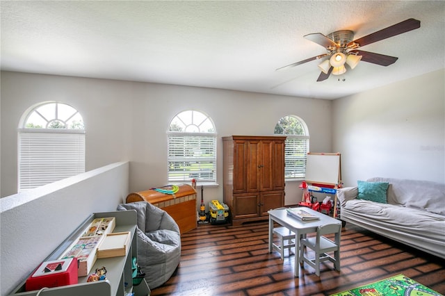 game room with a textured ceiling, a ceiling fan, and dark wood-style flooring