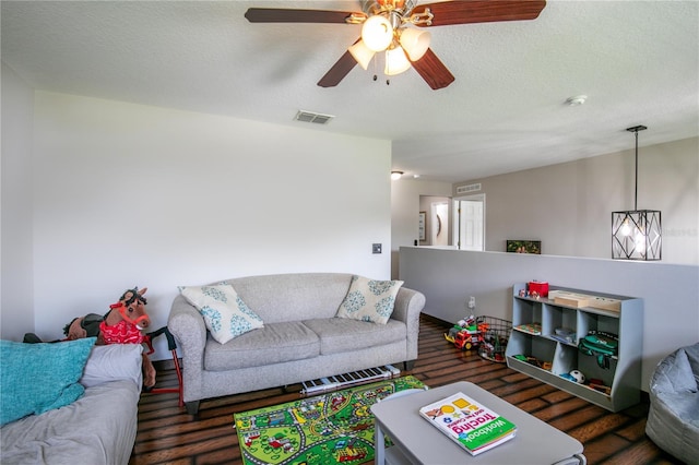 living area featuring a ceiling fan, visible vents, a textured ceiling, and wood finished floors