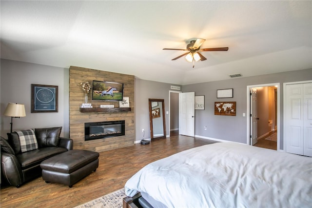 bedroom featuring baseboards, visible vents, connected bathroom, wood finished floors, and a fireplace