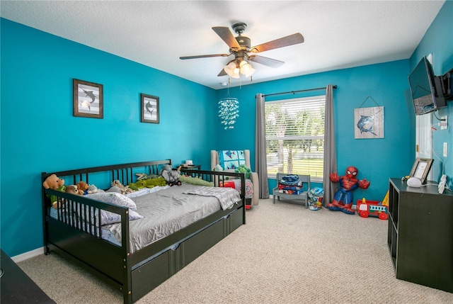 carpeted bedroom with ceiling fan, a textured ceiling, and baseboards