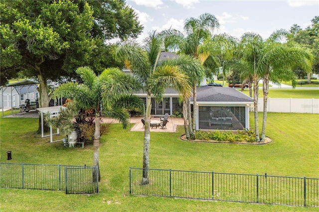 view of yard featuring a sunroom, a fenced backyard, and a patio